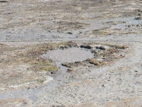 Bulgocząca błotnista woda w zagłębieniu na dnie krateru