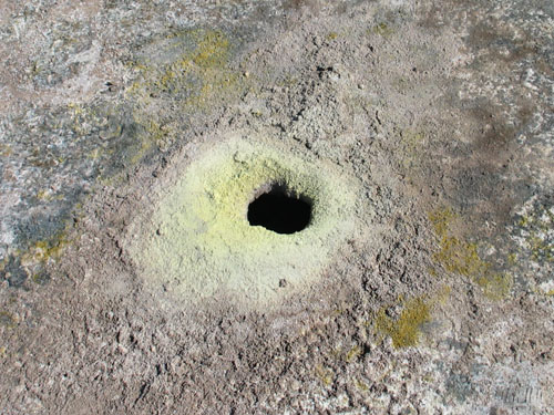 Niewielki otwór w dnie krateru; w sąsiedztwie widać żółty nalot siarki